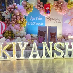 A close-up of the 'KIYANSH' marquee letters and the themed cylindrical stands used as props on the birthday stage.