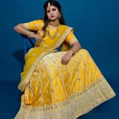 A model showcasing a traditional yellow and off-white lehenga with intricate mirror work. This outfit is an excellent choice for haldi ceremonies or festive wedding events, complete with matching jewelry.