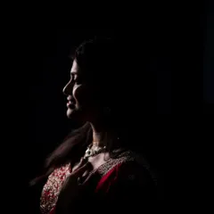 This portrait is an exercise in minimalism and mood. Using a single, carefully placed light, we sculpted the bride's profile out of the darkness, highlighting the rich color of her saree and her serene expression. This is our signature low-light portrait style.