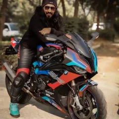 A smiling, happy shot of the rider with his bike. This shows a more personable and joyful side to the biker lifestyle.