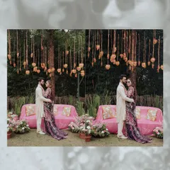 A diptych of the couple posing under a beautiful floral installation at their Haldi ceremony. The pink sofas and hanging hearts create a romantic and festive backdrop.