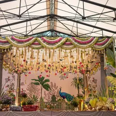 A full view of the stunning South Indian mandap we created, set within a beautiful glasshouse venue. The traditional floral decor, Pichwai-inspired art, and surrounding greenery came together to create a sacred and aesthetically divine atmosphere.