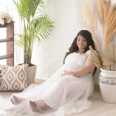 A serene solo portrait in a beautiful white gown. The bright, airy feel of this boho setup with its plants and pillows creates a peaceful and relaxed setting.