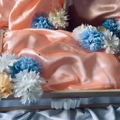 An elegant baby shower trousseau setup. This pinewood tray is lined with peach satin and decorated with blue and white flowers, ready to be filled with gifts for the mother-to-be.