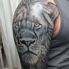 A different angle of the completed lion cover-up, showing how the design wraps around the shoulder. The use of light and shadow in this black and grey realism piece is key to its powerful presence.