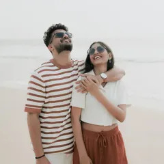 Soaking up the sun and sharing a laugh. Using sunglasses as a prop can add a cool, casual vibe to your beach engagement photos.