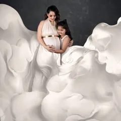 A tender moment between a mother and her daughter as they await the new arrival. The flowing white gowns create an angelic, cloud-like effect for this beautiful family maternity portrait.