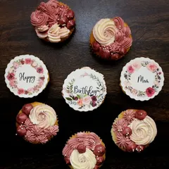A beautiful floral-themed set to wish a happy birthday to a client's mom. The box mixes cupcakes with delicate pink and white buttercream piping and others with elegant, printed floral wreath toppers.