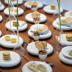 A closer view of the minimalist tablescape, showing a variety of small plates like macarons, parfaits, and savory bites. The arrangement is clean, organized, and visually satisfying.