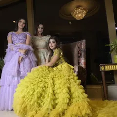 A group of models showcasing my collection of multi-layered ruffle and frill gowns. The yellow gown with its long, textured trail is a standout piece for a mehendi or pre-wedding shoot.