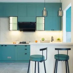 A sleek teal green kitchen from the Bren Zahara project. The design includes a breakfast bar with comfortable stools, black accents, and a stunning white quartz fluted backsplash for an elevated, modern look.