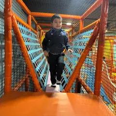 Watch your step! A young adventurer confidently crosses one of the netted bridges in our expansive soft play zone, building balance and coordination.