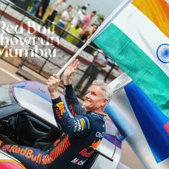 An iconic moment with F1 legend David Coulthard celebrating with the Indian flag at the Red Bull Showrun. This is the hero shot, the emotional peak of the event that tells a powerful story and creates a lasting memory.