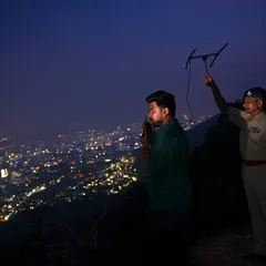A wildlife researcher and a forest department official track a radio-collared leopard at night. This collaborative project is essential for understanding how leopards use the urban landscape, providing data for better management and conflict mitigation.