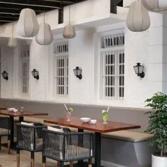 What was once a simple veranda is now a chic outdoor seating area. I kept the original white textured walls and windows, pairing them with modern woven chairs and fabric pendant lights to create a breezy, tropical feel.