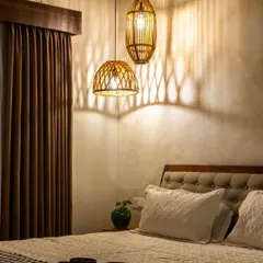 The magic of lighting in a master bedroom. This photo shows how the warm glow from the rattan pendant lights creates dramatic shadows on the textured wall, transforming the space into an intimate and cozy retreat at night.