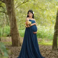 An outdoor portrait in a beautiful woodland setting. The mother-to-be holds a bouquet of flowers, adding a touch of color and softness to this nature-inspired maternity shoot.
