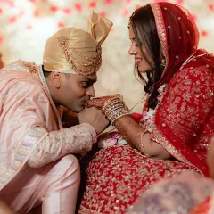 A tender moment between the groom and bride during their Hindu wedding ceremony. The groom's gentle kiss on her hand is a gesture of love and respect.