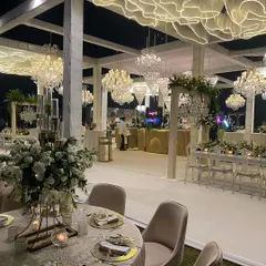 A breathtaking reception design featuring a unique ceiling installation of sculpted white fabric that glows from within. This is complemented by a forest of crystal chandeliers of varying sizes, creating a truly magical, cloud-like effect.
