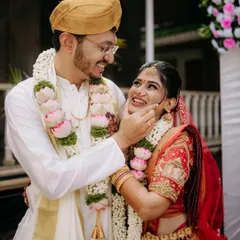 The groom gently touches the bride's cheek in a moment of pure affection, their smiles reflecting the joy of the wedding ceremony.