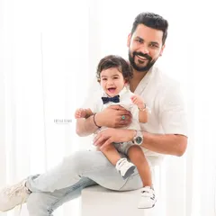 A proud father holds his laughing son. This light and airy portrait is a beautiful testament to the father-son bond.