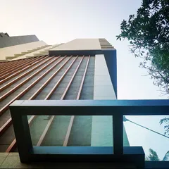 A low-angle shot of the façade, emphasizing the texture of the wooden fins and the modern architectural form of the residential building.