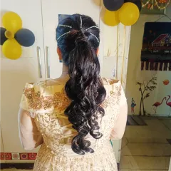 A voluminous curled ponytail with delicate pearl strings wrapped around the base. This adds a touch of sophistication to a classic party hairstyle.