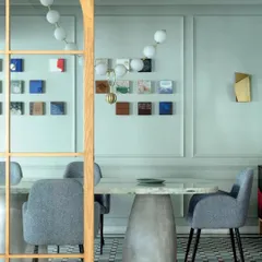 The dining room of Summer Haus, featured in Elle Decor. The space combines a sculptural concrete table with elegant chairs and a gallery wall of small artworks, creating a unique and personal atmosphere.
