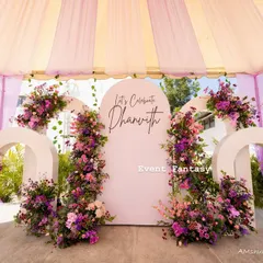 For a modern take on a naming ceremony, I created this lovely pastel-themed stage. The design features a series of white arches adorned with beautiful arrangements of pink and purple flowers, creating a fresh and celebratory look.