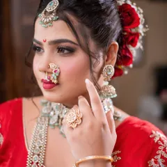 A close-up of a classic Maharashtrian bridal look with a smokey eye and bold red lip, complete with a traditional nath and chandrakor bindi.