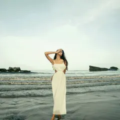 A full-length portrait on the beach, capturing a sense of peace and solitude. The vastness of the sea and sky creates a beautiful, cinematic frame.