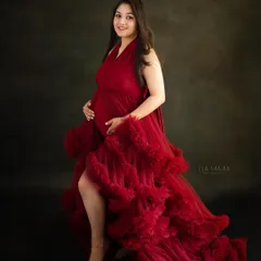 This portrait showcases the beautiful silhouette of pregnancy. The ruffled red gown adds texture and drama, making for a truly memorable maternity photo.