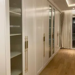 Closet so fancy, it probably charges rent to your clothes. This expansive white wardrobe features a mix of closed and mirrored doors with elegant brass handles.