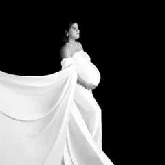 A high-contrast black and white portrait using a flowing white drape. The dark background makes the subject stand out, creating a powerful and artistic image.