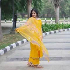 A full-length shot of a model in a vibrant yellow salwar suit. The movement in the dupatta adds a dynamic feel to this outdoor fashion photograph.