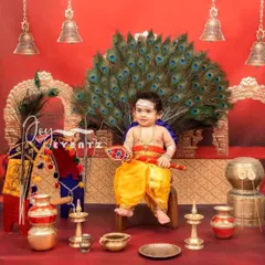 A grand and divine Little Muruga themed photoshoot for kids. This elaborate setup features a peacock feather throne, traditional brass lamps, and temple bells, creating a powerful and culturally rich portrait.