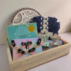 This large Diwali gift hamper includes a macrame purse, a mirror mosaic wall piece, a full necklace set, hair bows, and a box of sweets, all beautifully arranged in a wooden tray.
