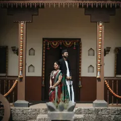 A stately portrait of a couple in traditional Maharashtrian attire outside a classic wada (a traditional mansion), capturing a sense of timeless grace.