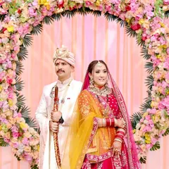 A classic stage portrait of the bride and groom framed by a beautiful circular floral arch. This is a perfect example of a formal wedding photograph that captures the grandeur of the decor.