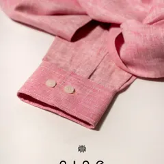 This salmon pink linen shirt is perfect for summer. The close-up shows the texture of the fabric and the quality of the stitching on the cuff.