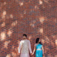 A stylish, composed shot of a couple holding hands against a modern brick wall, with beautiful light and shadow play.