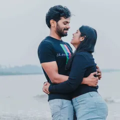 A candid photo of a couple sharing a look of love and laughter during their casual pre-wedding shoot on the beach.