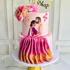 This engagement cake features a hand-painted edible portrait of the couple, making it incredibly personal. The design is completed with a flowing, realistic saree drape made from fondant with a golden border, blending artistry with tradition.