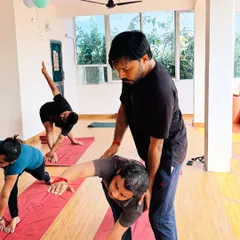 A hands-on correction in Trikonasana (Triangle Pose) helps with proper torso rotation and shoulder alignment, allowing for a deeper and more beneficial stretch.