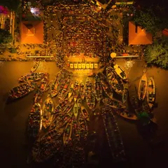 An aerial night view of the Ganga Aarti, showing the ghats packed with devotees and the river filled with boats. The entire scene glows, creating a symphony of light and spirit.