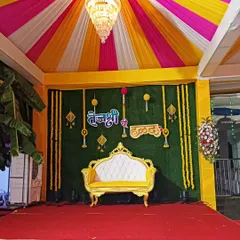 Here is a vibrant Haldi ceremony stage I put together. I used a combination of yellow, pink, and white fabric for the tent ceiling, a green backdrop for contrast, and traditional marigold flower hangings to complete the festive look.