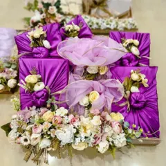 This is what we mean by luxury gifting. For this wedding trousseau, we wrapped each gift in rich purple satin fabric, decorated with floral arrangements, and presented them on an elegant wooden tray.