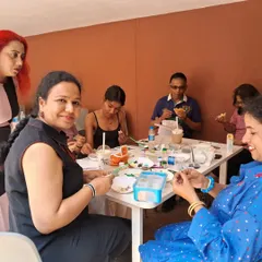 A candid moment from one of our interactive art classes. Participants are gathered around a table, sharing supplies and conversation as they work on their individual projects in a relaxed, communal setting.