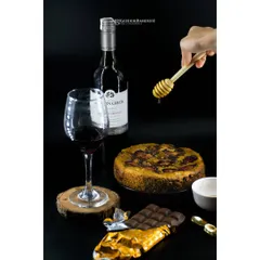 An elegant spread featuring a plum cake, red wine, and dark chocolate. The honey drizzle action shot adds a touch of sweetness and motion to this sophisticated dessert composition.