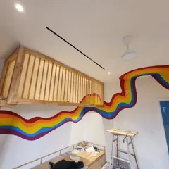 The rainbow mural as it curves around the loft structure, creating a continuous band of color.